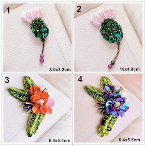 以下が含まれることがあります： 花柄の刺繍が施されたパッチが4つあります。最初のパッチは、ピンクとグリーンの薊で、サイズは8.0 x 3.2 cmです。2番目のパッチは、ピンクとグリーンの薊で、サイズは10 x 4 cmです。3番目のパッチは、グリーンとオレンジの花柄で、サイズは6.4 x 5.5 cmです。4番目のパッチは、グリーンとパープルの花柄で、サイズは6.4 x 5.5 cmです。