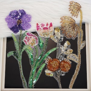 May include: A set of floral appliques featuring intricate beadwork and sequins. The design includes a large purple flower, two pink and white tulips with green stems, and two golden-toned flowers with metallic stems, all crafted on sheer mesh.