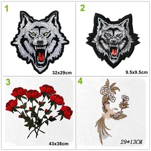 May include: Four embroidered iron-on patches. The first two patches are of a wolf's head with a white and gray fur design. The third patch is a bouquet of red roses. The fourth patch is a bird with a long tail and white flowers. The patches are different sizes.