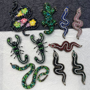 May include: Assortment of colourful beaded animal appliques, including a scorpion, a lizard, a snake, and a variety of other designs. These appliques are perfect for adding a touch of whimsy to clothing, bags, or other crafts.