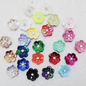 Puede incluir: Surtido de lentejuelas con forma de flor de colores con un centro de strass. Las lentejuelas son iridiscentes y vienen en una variedad de colores, incluyendo rosa, azul, verde, rojo y amarillo.