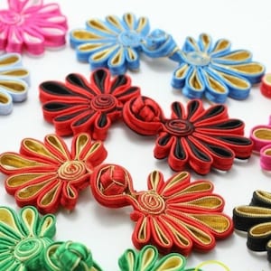 May include: Assortment of colorful fabric flower buttons with gold accents. The buttons are made of silk and are perfect for adding a touch of elegance to any garment.