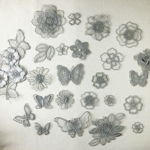May include: Assortment of silver lace appliques featuring floral and butterfly designs. The appliques are perfect for adding a touch of elegance to clothing, accessories, and home decor projects.