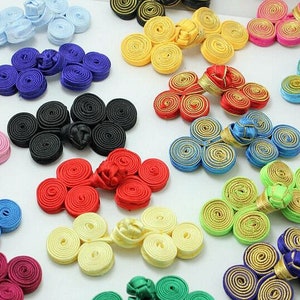 May include: Assortment of colorful fabric covered buttons with a spiral design. The buttons are in various colors, including red, blue, green, yellow, and white.