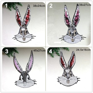 Könnte beinhalten: Vier Bügelbilder mit einem Cartoon-Kaninchen mit grauem Gesicht, weißen Zähnen und schwarzen Augen. Die Bügelbilder sind in vier Größen erhältlich: 38x24cm, 38x27cm, 45x27cm und 24,5x16cm. Die Ohren des Kaninchens sind aus Pailletten in verschiedenen Farben: Rot, Pink und Silber.