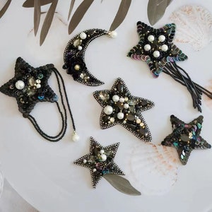 Könnte beinhalten: Sechs schwarze und weiße gestickte Patches mit Sternen und einem Halbmond. Die Patches sind mit Pailletten, Perlen und Perlen verziert.