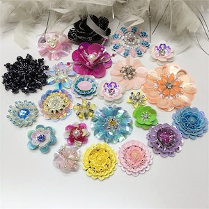May include: Assortment of colourful, beaded flower embellishments. The embellishments are made of sequins, beads, and pearls. They are perfect for adding a touch of sparkle to clothing, bags, and other crafts.