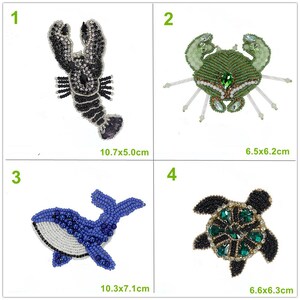 May include: Four embroidered iron-on patches featuring sea creatures. The patches are black and white lobster, green crab, blue whale, and green turtle. The patches are approximately 6.5x6.2 cm, 10.7x5.0 cm, 10.3x7.1 cm, and 6.6x6.3 cm.
