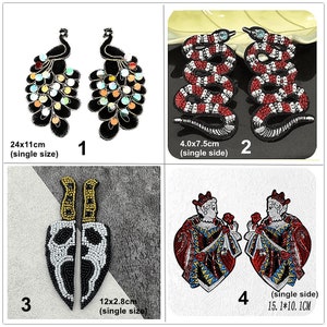May include: Four sets of iron-on patches, each with two pieces. The first set features a black peacock with iridescent sequins. The second set features a red and white snake. The third set features two black and white skull-shaped knives. The fourth set features two red and gold playing card queens.
