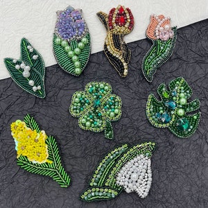 Puede incluir: Surtido de apliques de flores y hojas de cuentas. Los apliques están hechos con cuentas verdes, blancas, amarillas, rojas, negras y azules. Los apliques son perfectos para agregar un toque de encanto hecho a mano a la ropa, los bolsos y otras manualidades.