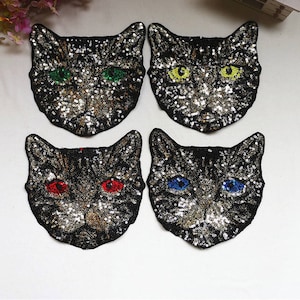 May include: Four black cat-shaped iron-on patches with colorful sequin details. The cats have different colored eyes: green, yellow, red, and blue.
