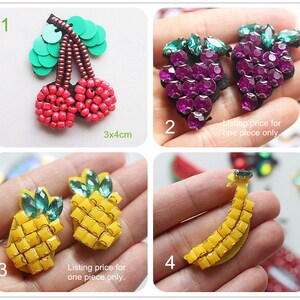 May include: A collection of beaded fruit-shaped embellishments. Includes a pair of red cherries with green sequin leaves, two purple grape clusters, two yellow pineapples with green gem tops, and a yellow banana.