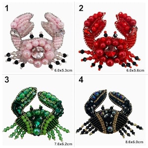 May include: Four beaded crab appliques in different colours. The crabs are pink, red, green, and black. Each crab is approximately 6 cm wide and 5 cm tall.