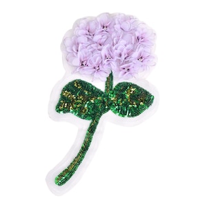 May include: A purple flower with green sequin leaves and a stem. The flower is made of fabric and has a 3D effect.