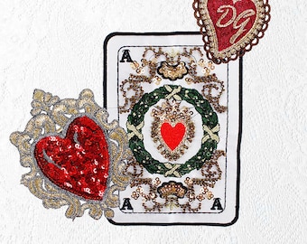 May include: A white card with a red heart and gold trim, surrounded by two gold and red heart-shaped embellishments. The card has the letter 'A' in each corner and the text 'DG' on the top embellishment.