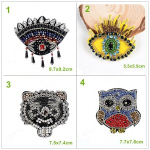 May include: Four embroidered iron-on patches with various designs. The patches are made with colourful beads and rhinestones. The designs include an eye, a tiger, an owl, and another eye. The patches are approximately 5.5x5.5 cm, 7.5x7.4 cm, 7.7x7.8 cm, and 9.7x9.2 cm.