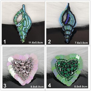 May include: Four beaded patches: 1) a green and light blue shell measuring 11.6x5.0cm, 2) a black, blue, and green shell measuring 7.6x3.0cm, 3) a pink sequin heart with clear crystals measuring 8.0x8.0cm, and 4) a green sequin heart with green crystals measuring 8.0x8.0cm.