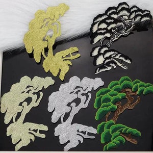 以下が含まれることがあります： 松の木の形をした刺繍のアイロン接着パッチが5つ。パッチは金色、銀色、黒色、緑色、茶色です。
