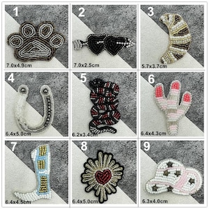 May include: A selection of beaded patches in diverse designs: a paw print, hearts, a crescent moon, a horseshoe, a snake, a cactus, a boot, a sunburst with a heart, and a hat. Each patch measures roughly 2.5 to 7 cm in length.