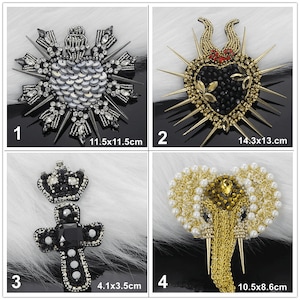 Puede incluir: Cuatro parches de hierro bordados con diferentes diseños. El primer parche es un corazón plateado con una corona de espinas, que mide 11,5 cm por 11,5 cm. El segundo parche es un corazón negro con una corona de espinas y acentos rojos, que mide 14,3 cm por 13 cm. El tercer parche es una cruz negra con una corona y una piedra negra, que mide 4,1 cm por 3,5 cm. El cuarto parche es un elefante dorado con acentos de perlas, que mide 10,5 cm por 8,6 cm.