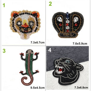 Puede incluir: Cuatro parches termoadhesivos con diseños de animales y una corona de cuentas. Los parches son negros, blancos, dorados, rojos, verdes y azules. Los parches miden 7,3 x 6,7 cm, 7,0 x 5,9 cm, 9,5 x 4,5 cm y 7,3 x 6,8 cm.