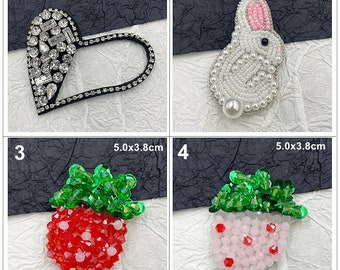 May include: Four embroidered patches with different designs. A black heart with rhinestones, a white rabbit with pearl beads, a red strawberry with green leaves and red and white beads, and a pink strawberry with green leaves and pink and white beads. The patches are all approximately 5 cm in diameter.