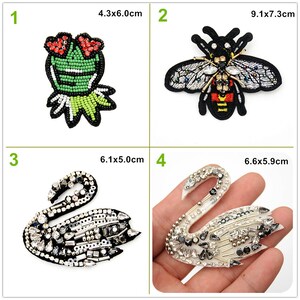 Könnte beinhalten: Vier gestickte Bügelbilder. Das erste Bügelbild ist ein grüner Frosch mit roten Blumen auf dem Kopf. Das zweite Bügelbild ist eine Biene mit schwarzen und gelben Streifen. Das dritte Bügelbild ist ein schwarzer Schwan mit silbernen und weißen Strasssteinen. Das vierte Bügelbild ist ein weißer Schwan mit silbernen und schwarzen Strasssteinen.