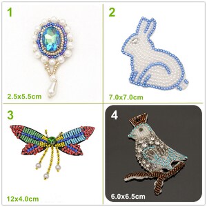Puede incluir: Cuatro adornos bordados. Un broche con una gema azul y detalles de perlas (2,5 x 5,5 cm). Un conejo blanco con ribete azul (7,0 x 7,0 cm). Una libélula colorida (12 x 4,0 cm). Un pájaro en una rama (6,0 x 6,5 cm).