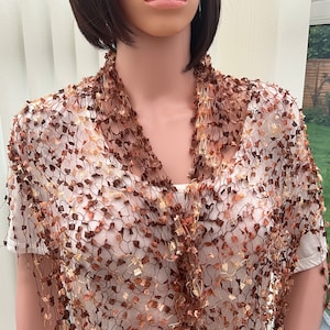May include: A brown and cream crocheted shawl with a delicate, open-weave pattern. The shawl is draped around a mannequin's neck and shoulders.