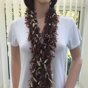 May include: A brown, beige and light blue fuzzy scarf with long strands of fringe.