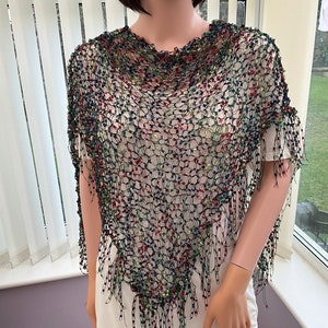 May include: A black crochet poncho with colorful beads and fringe. The poncho is made of a lightweight, airy material and has a loose, flowing fit.