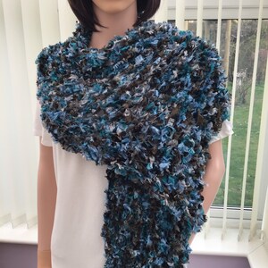 May include: A long, blue, brown, and white fuzzy scarf. The scarf is made of a soft, fluffy yarn and is perfect for keeping warm in the winter.