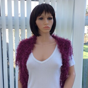 May include: A mannequin wearing a white shirt and a purple fuzzy shawl.