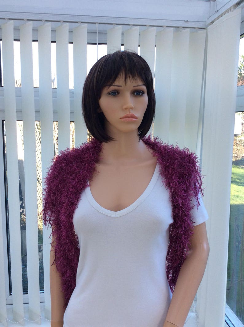 May include: A mannequin wearing a white shirt and a purple fuzzy shawl.