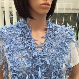 Peut inclure: Une &eacute;charpe en crochet bleu clair avec des d&eacute;tails en frange. L'&eacute;charpe est faite d'un mat&eacute;riau doux et l&eacute;ger, parfait pour ajouter une touche de style &agrave; n'importe quelle tenue.