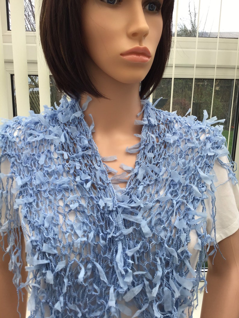 Peut inclure: Une &eacute;charpe en crochet bleu clair avec des d&eacute;tails en frange. L'&eacute;charpe est faite d'un mat&eacute;riau doux et l&eacute;ger, parfait pour ajouter une touche de style &agrave; n'importe quelle tenue.