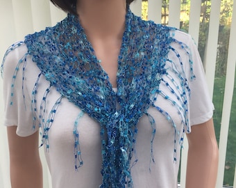 May include: A blue and turquoise crocheted scarf with fringe. The scarf is made of a delicate, open-weave fabric and has a light, airy feel.