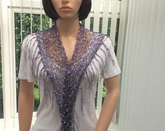 May include: A purple crocheted scarf with fringe. The scarf is draped around a mannequin's neck.