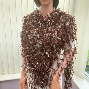 May include: A brown and white fringed shawl with a loose knit texture.