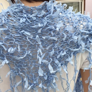 Peut inclure: Un ch&acirc;le en crochet bleu clair avec une bordure en franges. Le ch&acirc;le est fait d'un tissu d&eacute;licat et ajour&eacute;.
