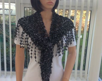 May include: A black crocheted shawl with a fringe. The shawl is draped over a mannequin's shoulders.