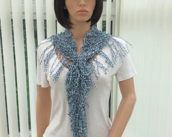May include: A blue and white fringed scarf with a delicate pattern. The scarf is tied around the neck of a mannequin.
