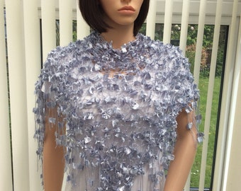 May include: A light blue crocheted shawl with a fringe border. The shawl is made of a delicate, open-weave fabric and has a flowing, elegant design.