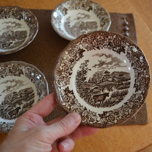 May include: Set of four brown and white ceramic bowls with a floral design and a countryside scene with a castle and animals.