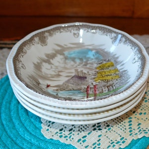 May include: A set of four white ceramic bowls with a brown and gray floral pattern. The bowls feature a scene of a castle and trees by a body of water.