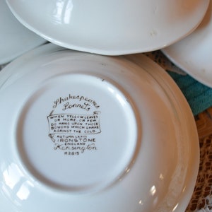 May include: White ceramic saucer with a brown Shakespeare's Sonnets quote and Ironstone Kensington logo. The quote reads: "WHEN YELLOW LEAVES ON MORE.OR FEW DO HANG UPON THOSE BOUGHS WHICH SHAKE AGAINST THE COLD. AUTUMN LEA IRONSTONE Kensington 2815"