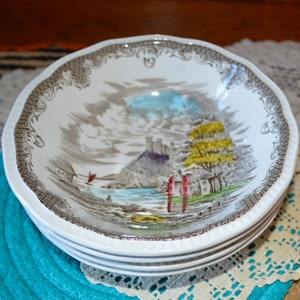 May include: A set of four white ceramic bowls with a brown and gray floral pattern. The bowls feature a scene of a castle on a hill with a lake and trees.