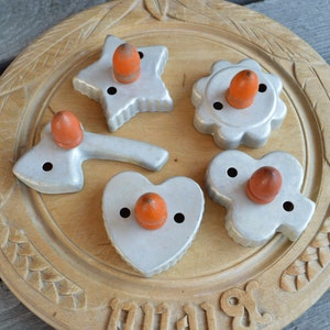 Peut inclure: Cinq emporte-pièces anciens de différentes formes, chacun avec une poignée orange. Les emporte-pièces sont disposés sur un plateau rond en bois sculpté. Les formes incluent une étoile, une fleur et un cœur.