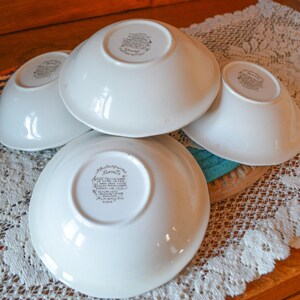 May include: Four white ceramic bowls with a floral design and the text "Shakespeare" on the bottom. The bowls are stacked on top of each other.
