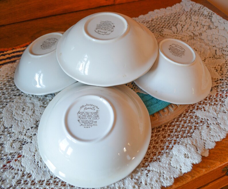 May include: Four white ceramic bowls with a floral design and the text "Shakespeare" on the bottom. The bowls are stacked on top of each other.